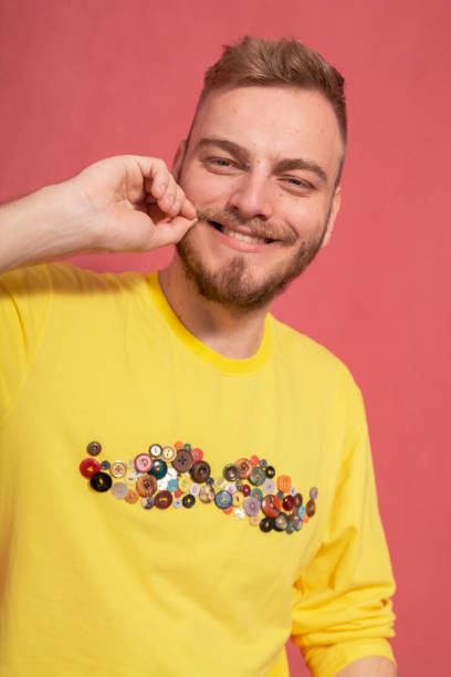 istock one young man, smiling to camera, while holding his mustache with his hand. 1153761941