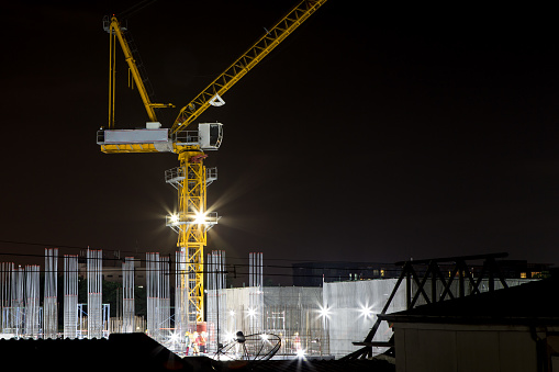 Crane and spotlight on buildings under construction at night