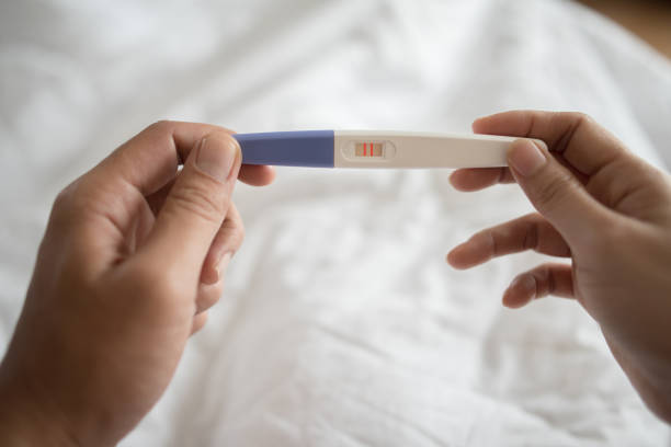 istock Young woman hand holding pregnancy test 1153764976