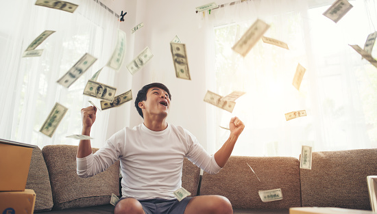 Hombre feliz con dólares en efectivo volando en la oficina en casa, Rico de concepto en línea de negocios photo
