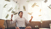 Happy man with cash dollars flying in home office, Rich from business online concept