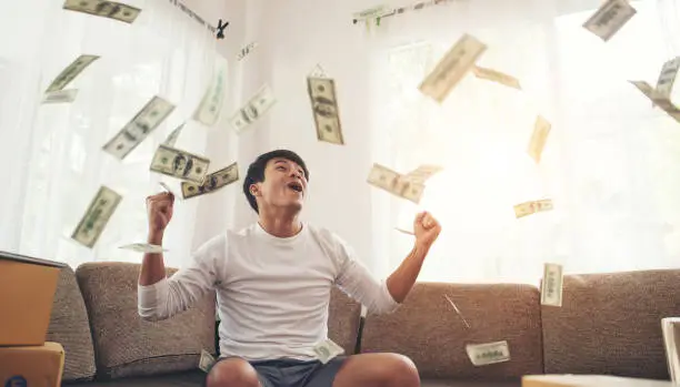 Photo of Happy man with cash dollars flying in home office, Rich from business online concept