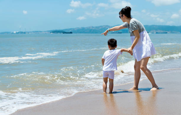 istock Mother and son walking on beach 1153772578