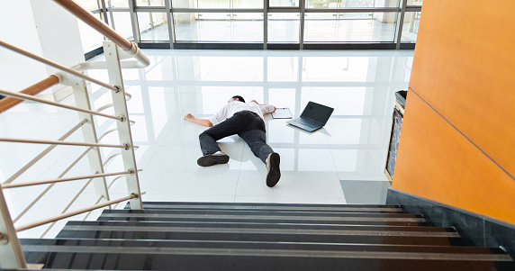 Man slips falling on wet floor in a modern office building.