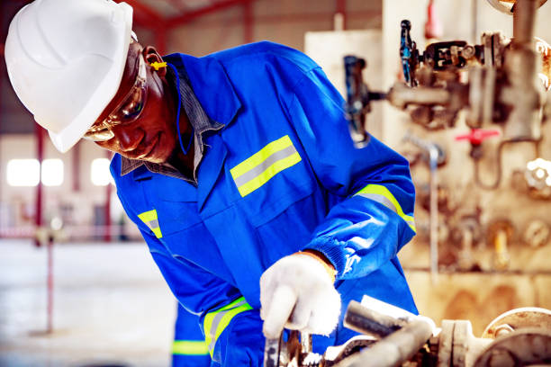 geschickter pump-room-betreiber schließt druckventil in einer fabrik in afrika - minority african ethnicity business hardhat stock-fotos und bilder