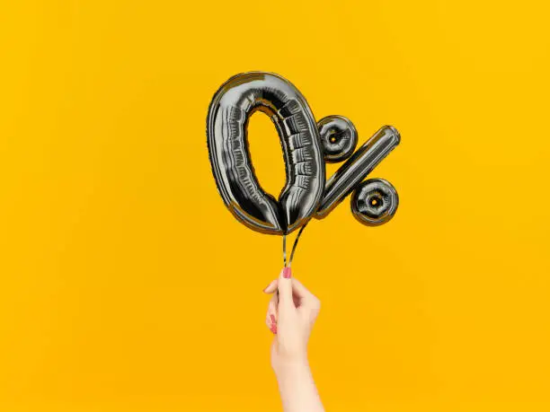 Female hand holding Zero percent symbol. 0 % banner black flying foil balloons on yellow. 3d rendering.