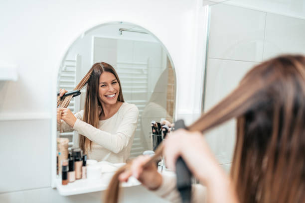 reflection of young smiling woman straightening her hair in the bathroom. - 2521 imagens e fotografias de stock
