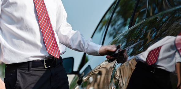 Closeup of a businessman opening a car door.