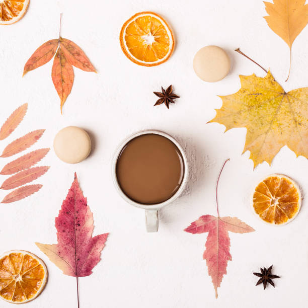 istock Cup of Coffee and macaroons cookies on white table with autumn leaves pattern 1153785048
