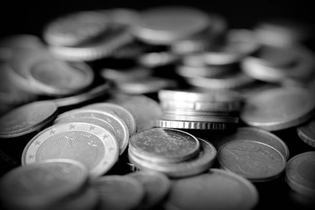 istock Euro coins scattered on a dark surface close up. Black and white 1153788120
