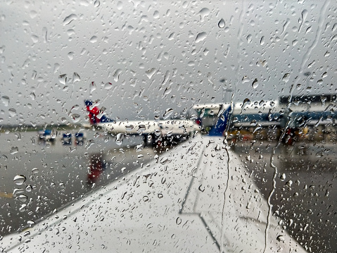 Taken this picture from the airplane when it was taxing out in heavy rain. From the window another airplane is visible parked in the terminal. The airplane in the picture is defocused.