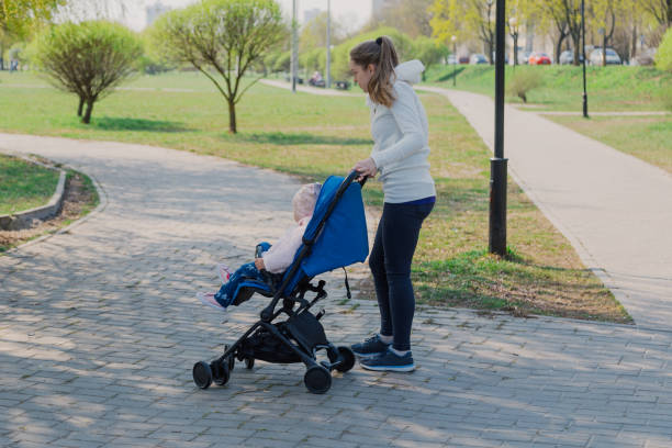 istock Young mother with a baby in a stroller in a summer park 1153793908