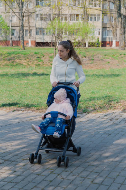 istock Young mother with a baby in a stroller in a summer park 1153793939
