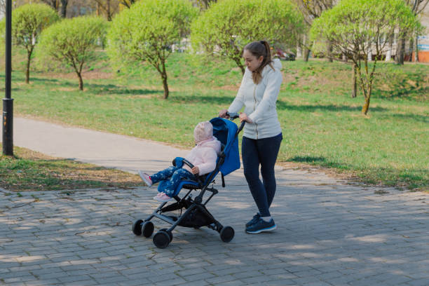 istock Young mother with a baby in a stroller in a summer park 1153793998