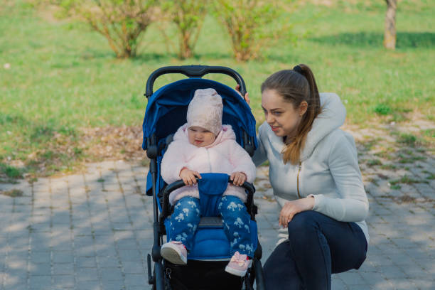 istock Young mother with a baby in a stroller in a summer park 1153794036
