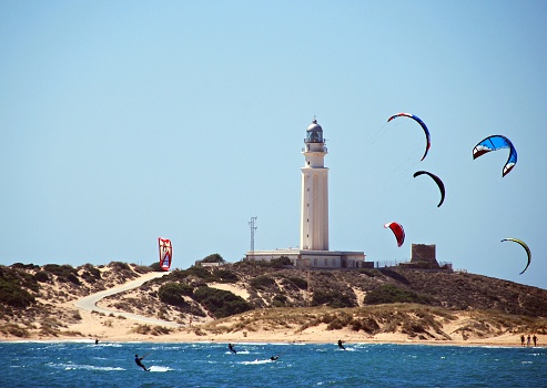 Kitesurfers and with views towards the beach and lighthouse, Cabo Trafalgar, Cadiz Province, Andalusia, Spain, Europe.