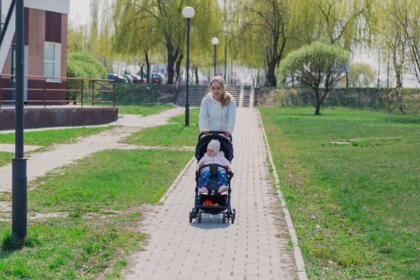istock Young mother with a baby in a stroller in a summer park 1153798792