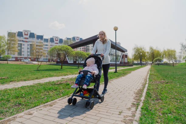 istock Young mother with a baby in a stroller in a summer park 1153798899