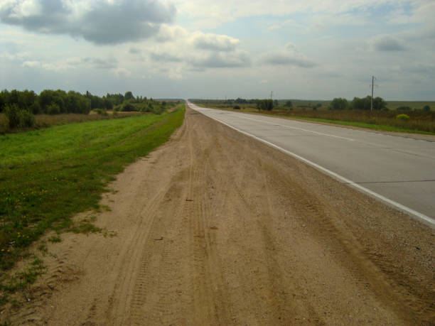 istock Direct asphalt road through the countryside under the sky, on which the clouds float. 1153799939