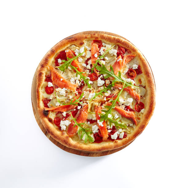 Seafood Pizza with Salmon, Pickled Artichokes, Arugula, Cherry Tomatoes, Mozzarella Cheese and Pesto Sauce Isolated on White Background. Traditional Italian Whole Flatbread on Wooden Plate Top View