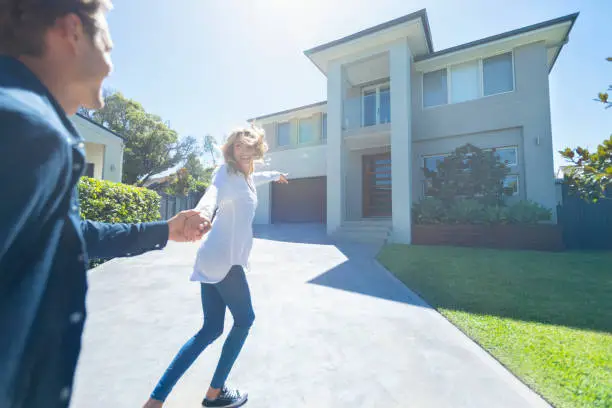 Photo of Couple joyfully running into their new home.