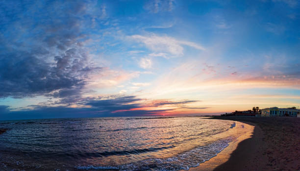 Panoramic pastel-colored sunset on the coast of Rome, with awesome sky , the calm sea and a relaxing atmosphere Panoramic blue sunset on Roman coast at Ostia Lido, with the intense sky the calm sea and a relaxing atmosphere breaking glass ceiling stock pictures, royalty-free photos & images