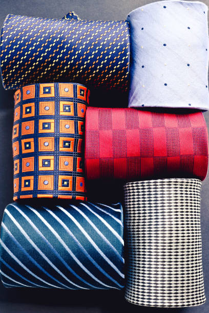 Showcase with multicolored ties. View of different colors ties in showcase. Showcase of rolled neckties at store. Twisted neckties beautifully stacked.
