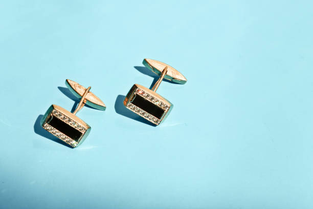 Males golden cufflinks with diamonds on light blue background.