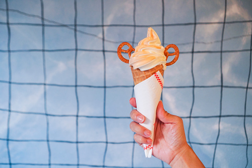 Woman holding a yogurt soft serve ice cream topped with cracker.