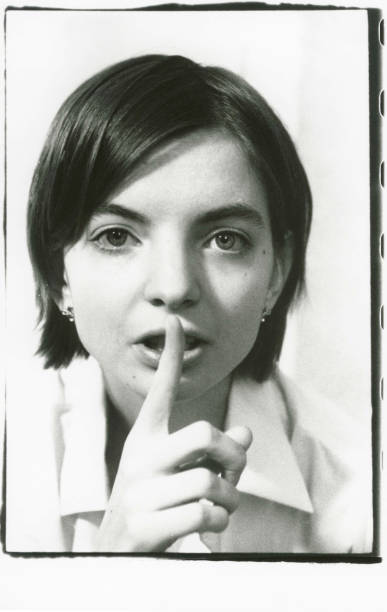 istock The girl holds a finger at the lips calling for silence. 1153811763