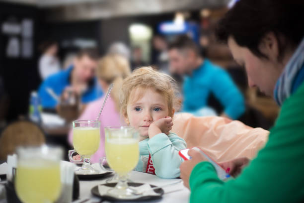 Little girl in a restaurant with her parents after skiing. A little girl is resting with her parents in a restaurant of a ski resort. bukovel ski resort ukraine stock pictures, royalty-free photos & images