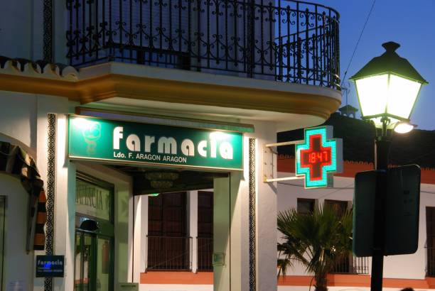 Pharmacy at dusk, La Cala de Mijas, Spain. Front view of a pharmacy shop in the town centre at dusk, La Cala de Mijas, Costa del Sol, Malaga Province, Andalucia, Spain. farmacia stock pictures, royalty-free photos & images