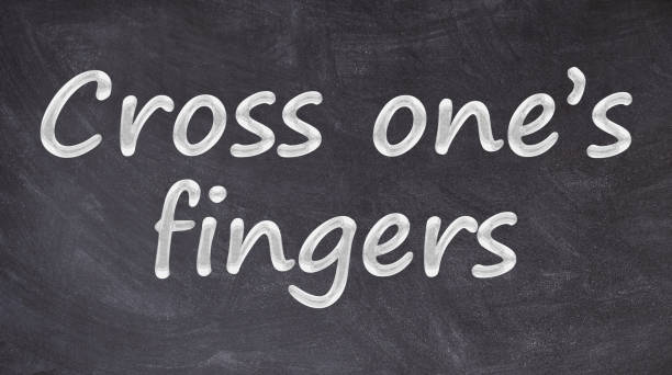istock Cross one’s fingers written on blackboard 1153813261