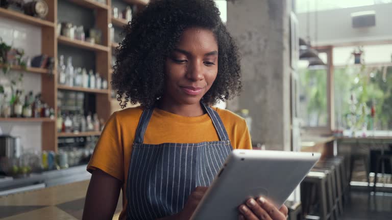 A smiling female cafe owner using digital tablet