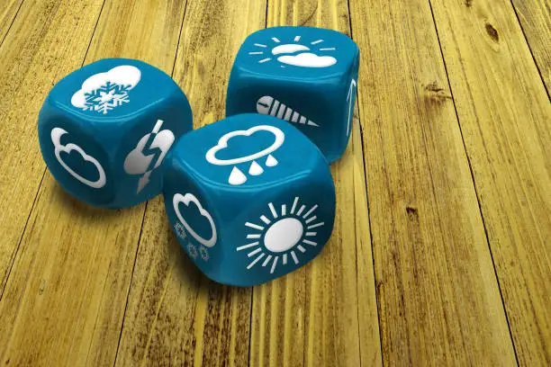 Photo of Wrong weather forecast concept poster. Inexact methods of prediction. Three dices with weather condition symbols on faces. Macro of blue gambling cubes on wooden table background