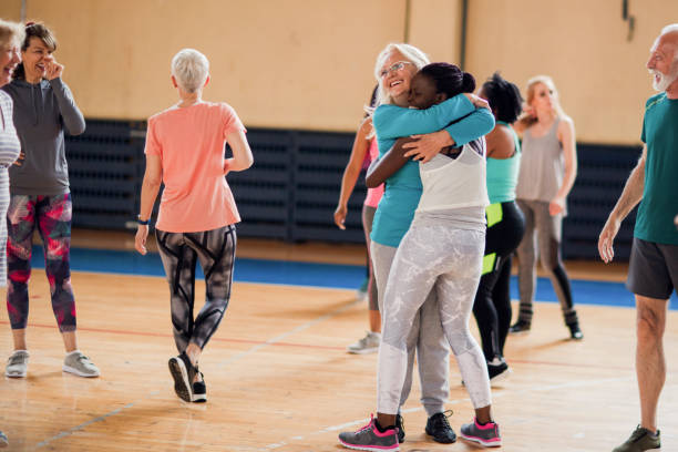 dame aînée soutenant la jeune femme sur leur classe de zumba - leisure facilities photos et images de collection