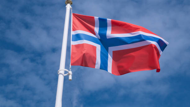 istock Norway flag waving in sunny blue sky. 1153821665