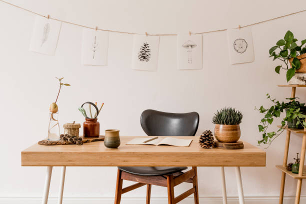 Stylish scandinavian home interior of open space, with a lot of plants, design accessories, bamboo shelf, wooden desk and hanging mock up forest drawings . Botany concept of home decor. Sunny room. Stylish and scandinavian interior of home office with mock up poster frame. Botany and forest concept of home decor. bamboo material photos stock pictures, royalty-free photos & images