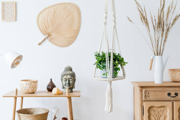 istock Stylish and minimalistic boho interior with design and handmade macrame shelf planter hanger for indoor plants, wooden furnitures, elegant accessories ,rattan basket and leaf. Cozy home decor. 1153828334