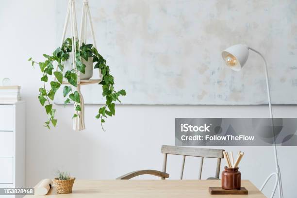 Stylish And Boho Home Interior Of Open Space With Wooden Desk Chair Lamp And White Shelf Design And Elegant Personal Accessories Botany And Minimalistic Home Decor Abstract Painting On The Wall Stock Photo - Download Image Now