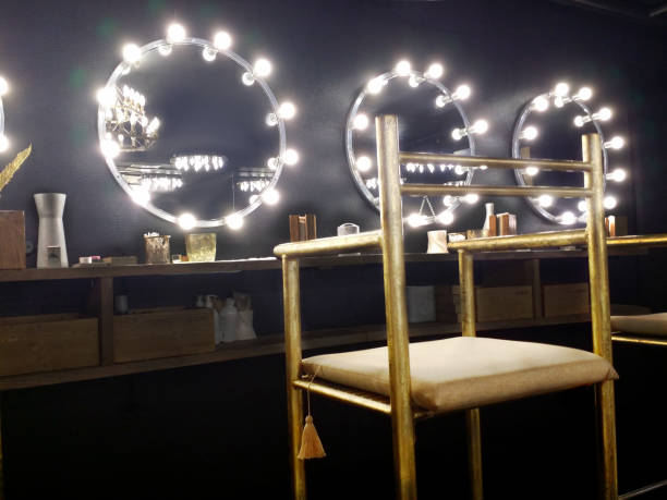 Atmospheric black interior in the beauty salon Atmospheric black interior in the beauty salon. High golden, shabby chair in the foreground. Mirror with light bulbs. Place for make up. backstage stock pictures, royalty-free photos & images