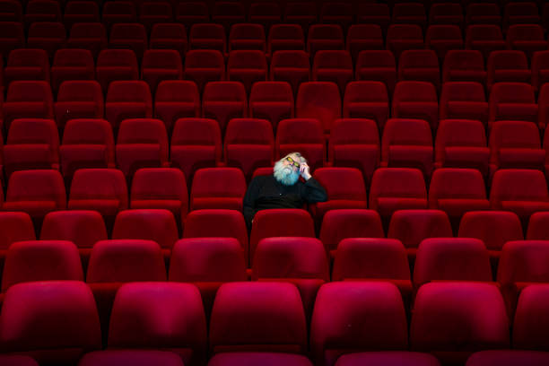 istock One man with white beard sits in Empty cinema or theatre with comfortable red seats, sleeping 1153829110