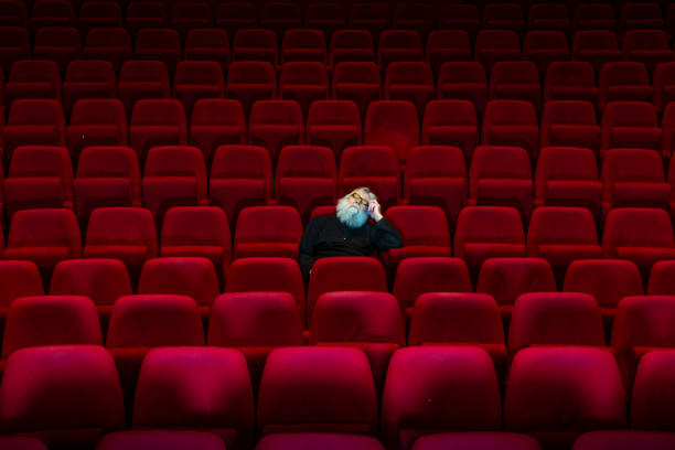 one man with white beard sits in empty cinema or theatre with comfortable red seats, sleeping - empty theater imagens e fotografias de stock