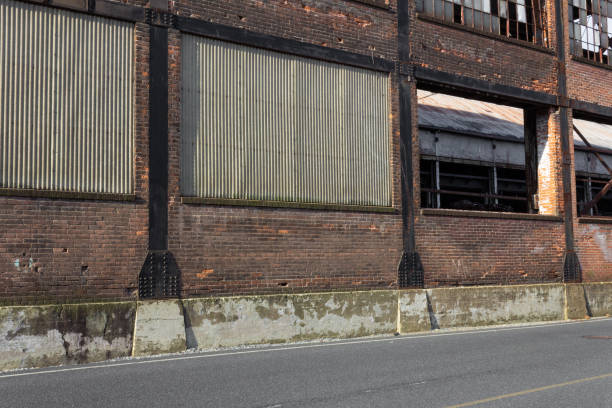 Street bordered by a brick wall, corrugated metal and open structure metal framework, horizontal aspect