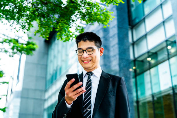 istock Smiling businessman text messaging through phone 1153833121