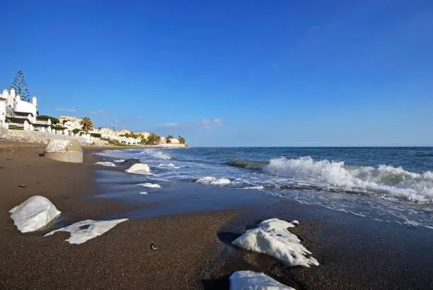 View along the beach towards apartments with large rocks along the shoreline, Sitio de Calahonda, Costa del Sol, Malaga Province, Andalucia, Spain, Europe