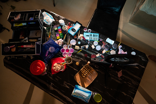 Directly above different kind of make up and beauty products on table in dark room