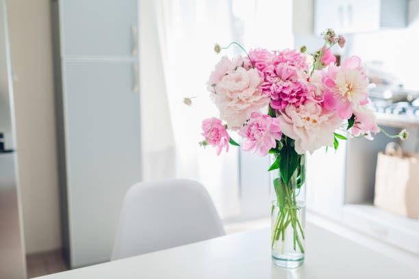 istock Pink peonies. Modern kitchen design. Interior of white and silver kitchen decorated with flowers. 1153839412