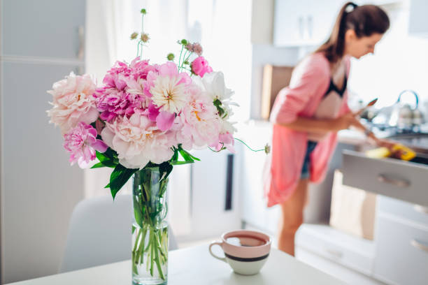 istock Modern kitchen decorated with pink peonies. Housewife cooking dinner. Interior design. 1153839699
