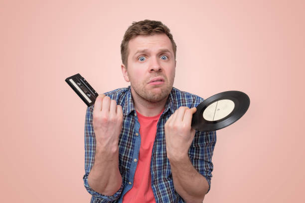 istock Man with tape cassette and old retro vinyl confused and puzzled 1153841995
